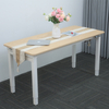 A light wood adjustable-height table with white legs in an indoor setting under normal lighting, decorated with flowers, a laptop, and a table runner.