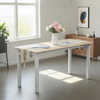 A light wood adjustable height table set up in a room with a window, plants, a cabinet, and abstract art, showcasing its use as a versatile furniture piece.