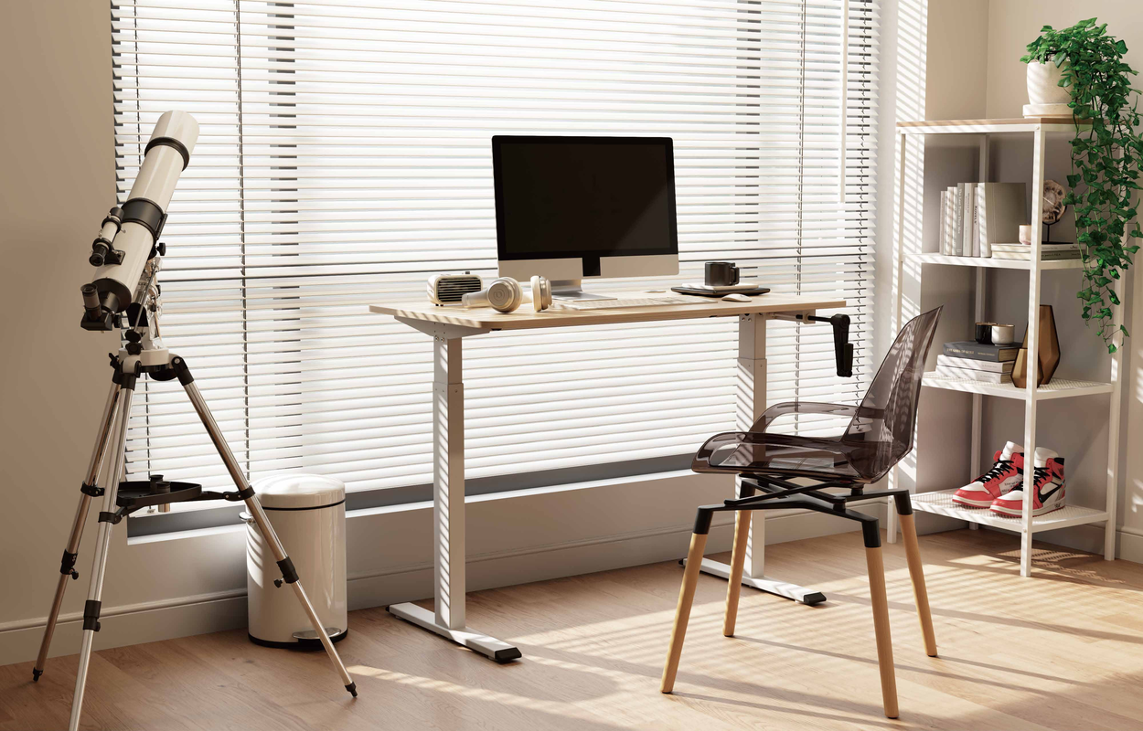 A lifestyle image of the white 2MABR2 desk fully assembled and set up with a computer, lamp, and plants in a bright, modern office setting.]alt: The 2MABR2 white manual standing desk in a bright, modern home office with a computer and plants, showcasing a clean and productive workspace.